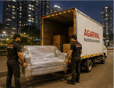 Agarwal Packers and Movers staff loading a sofa into a truck at night